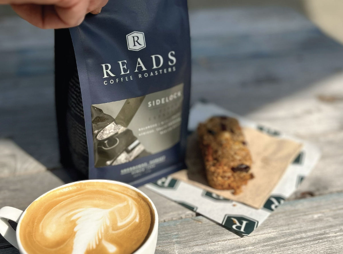 Reads Coffee Roasters package with a cup of coffee and cookie on a wooden surface