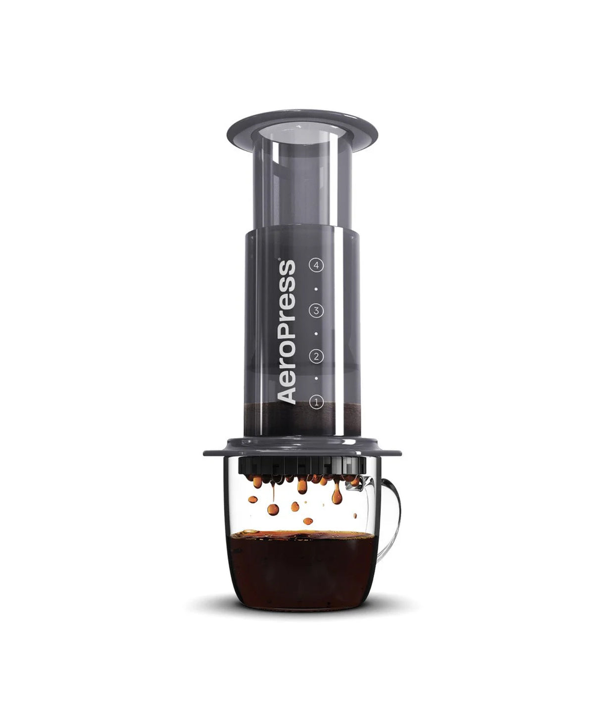 Aeropress coffee maker with a dark gray body and clear chamber, shown with brewed coffee dripping into a clear glass cup on a white background.