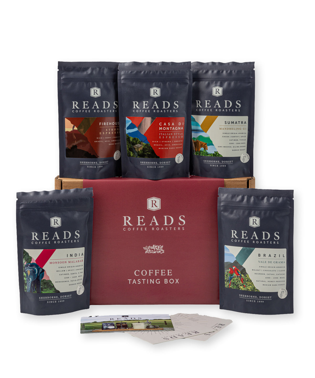 Reads Coffee Roasters Coffee Box gift set featuring a red cardboard box in the center, surrounded by five dark navy coffee bean bags in different flavors, with two small cards in front, on a white background.