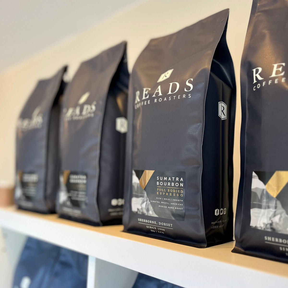 Row of READS Coffee Roasters coffee bags on a shelf.