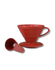 A red V60 pour-over coffee dripper with its matching saucer and funnel placed beside it on a clean white background.