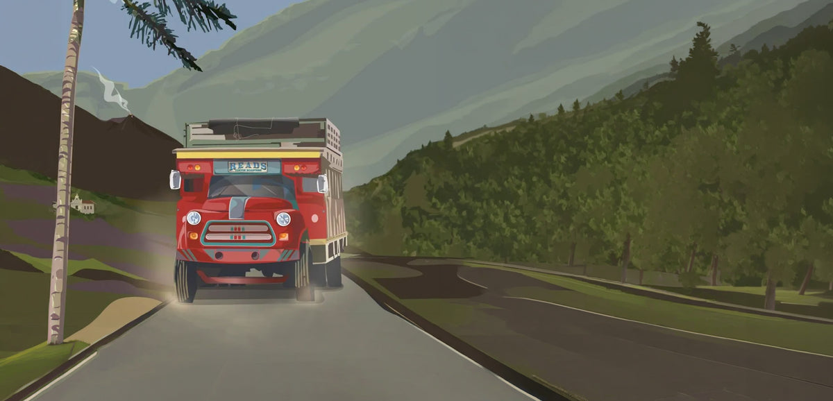 Red truck on a road with mountains and trees in the background
