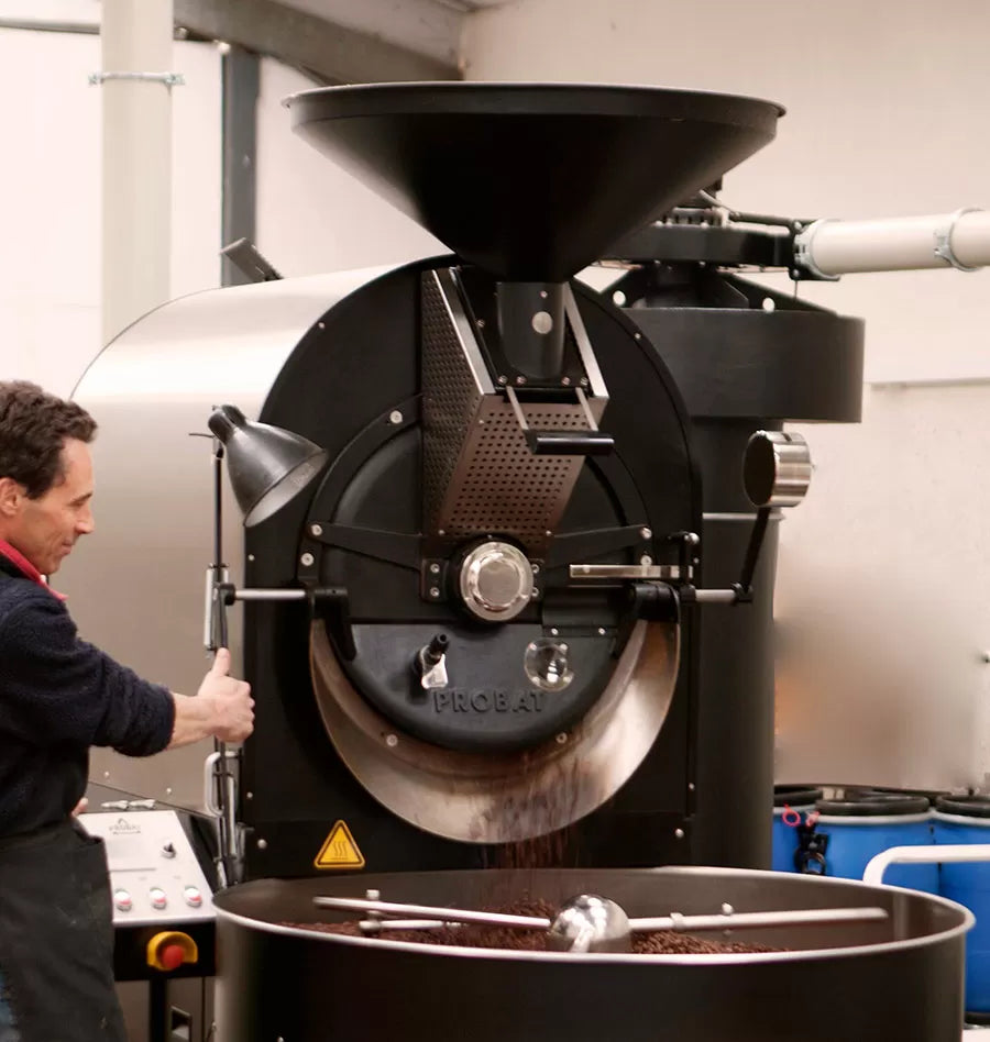 Person operating a coffee roasting machine in a workshop setting